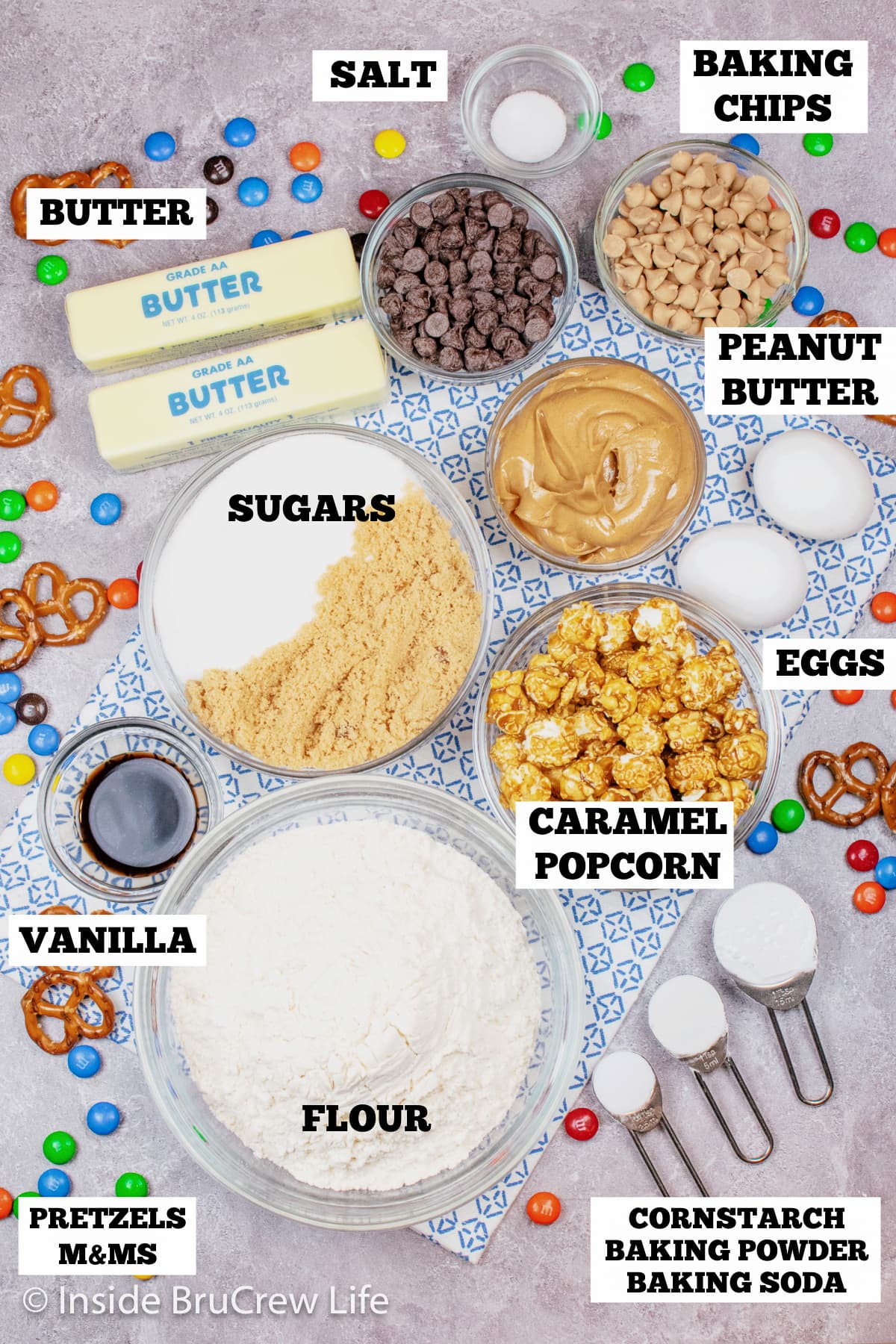 A gray board with bowls of ingredients needed to make caramel popcorn cookies.