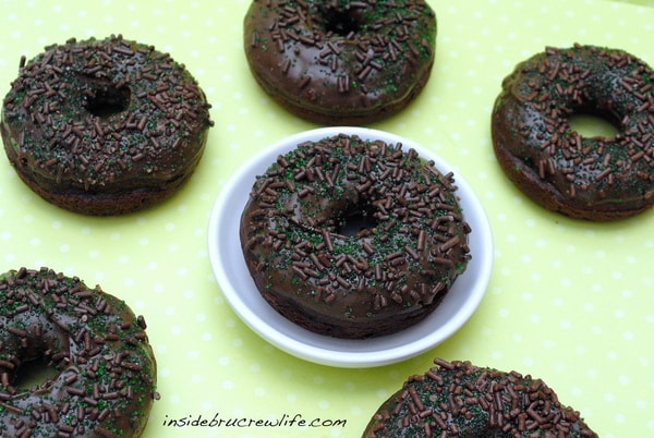 6 chocolate donuts on a green and white polka dot background.