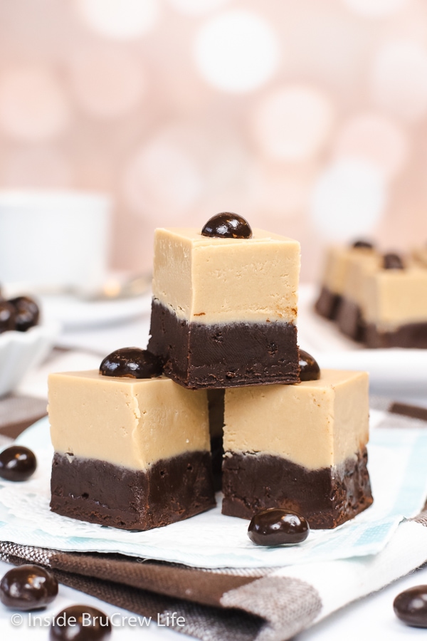 Three squares of fudge stacked on top of each other on a white paper.