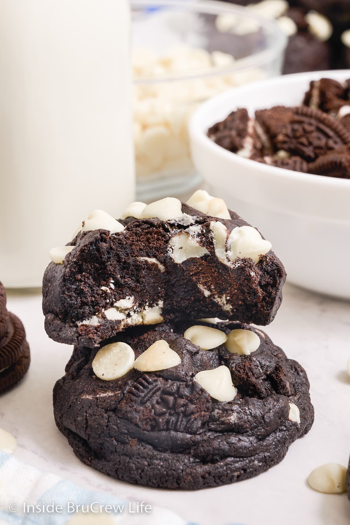 A stack of two puffy chocolate Oreo cookies with a bite out of the top one showing the inside.