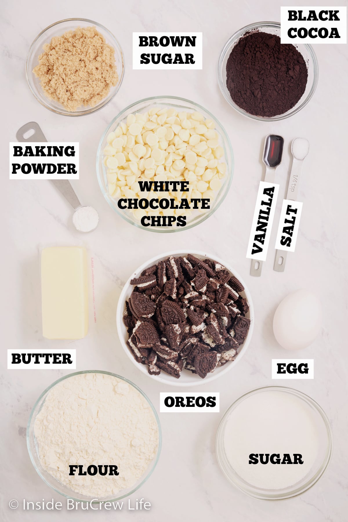 A white board with bowls of ingredients needed to make Oreo cookies with white chocolate.