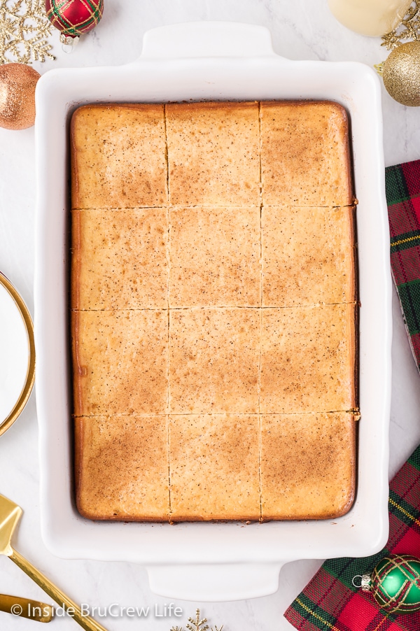 An overhead picture of a white pan filled with eggnog cheesecake brownies dusted with nutmeg.
