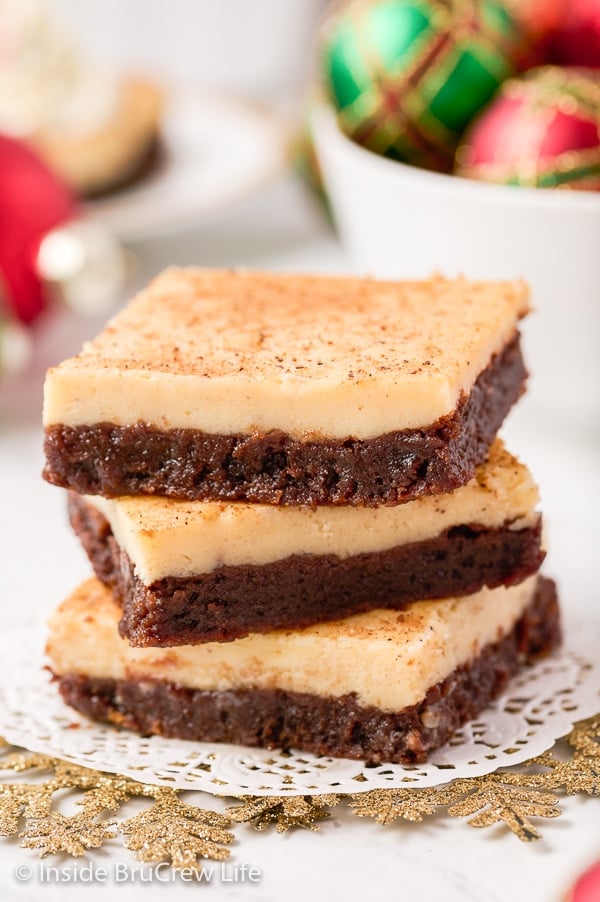 Three eggnog brownies stacked on top of each other on a white board.