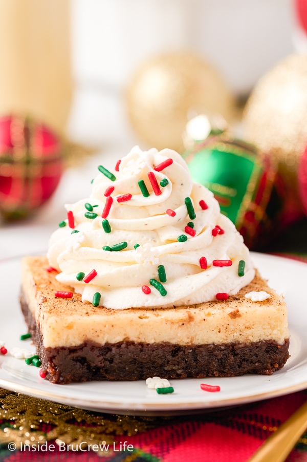 A white plate with a square of eggnog brownies topped with whipped cream and sprinkles.