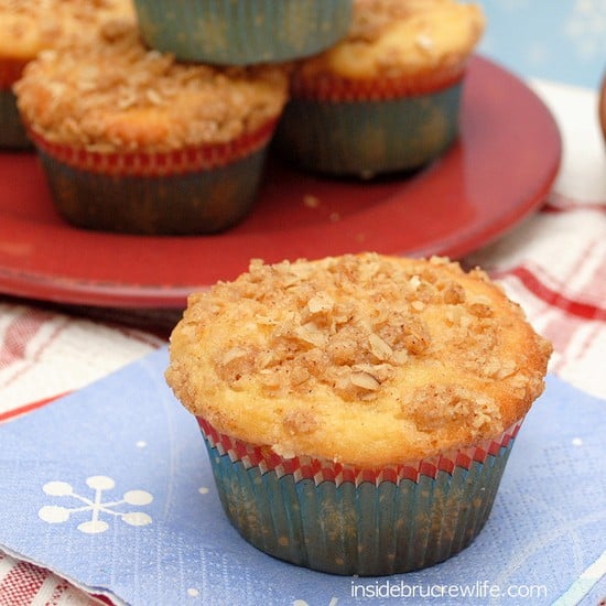 A red plate of Eggnog Crumble Muffins with a blue napkin in front of it and another muffin on it