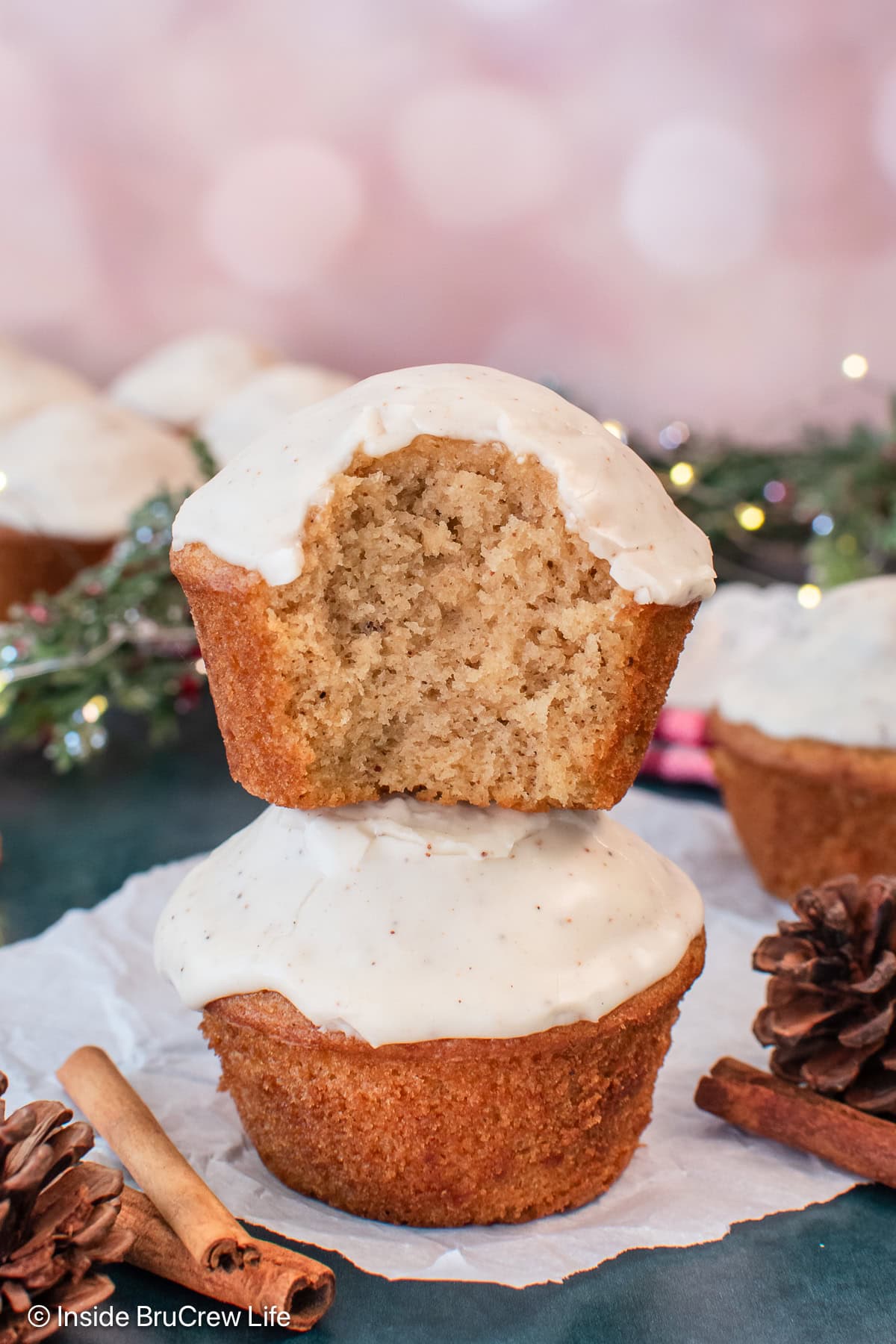 Two glazed muffins stacked toghter with a bite out of the top one.