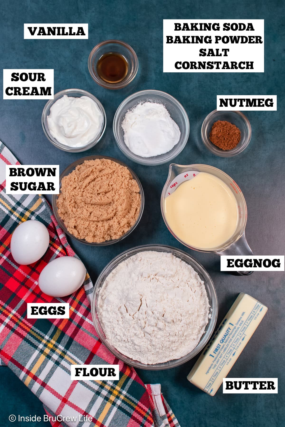 A green board with bowls of ingredients needed to make muffins with eggnog.