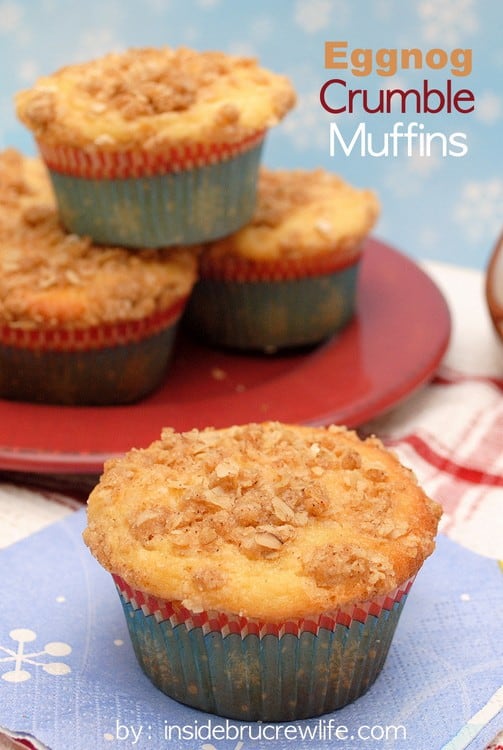 A red plate with Eggnog Crumble Muffins on it and a blue napkin in front with another muffin on it