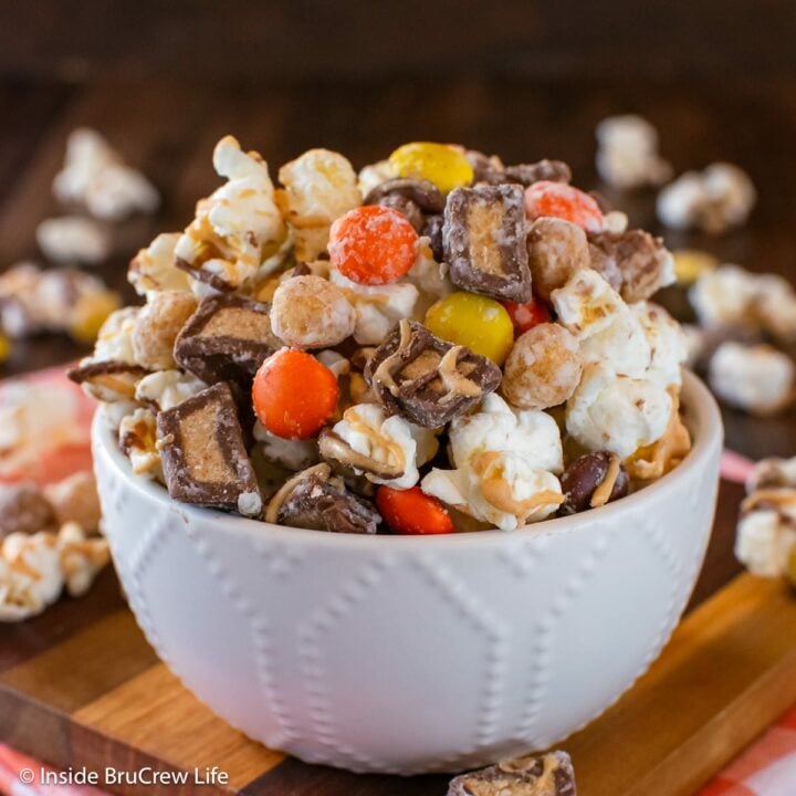 A white bowl filled with peanut butter candies and popcorn.