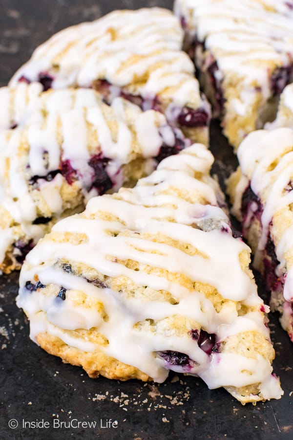 A black tray with coconut scones drizzled with glaze on it.