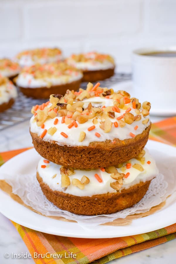 Two baked donuts with frosting stacked on a white plate.