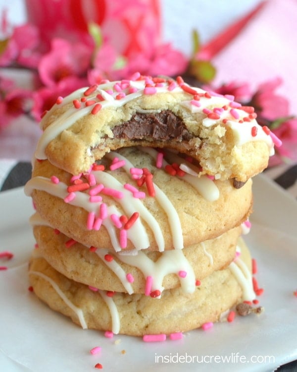 A close up picture of a stack of Coconut Nutella Cookies on a white plate with a bite out of the top cookie