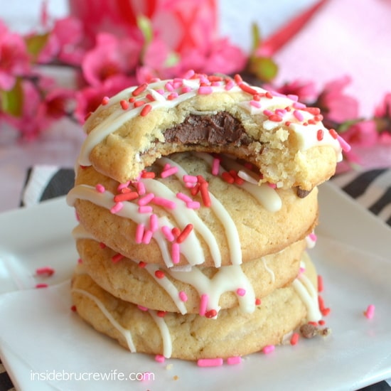 A stack of Coconut Nutella Cookies on a white plate with a bite out of the top cookie showing the chocolate inside