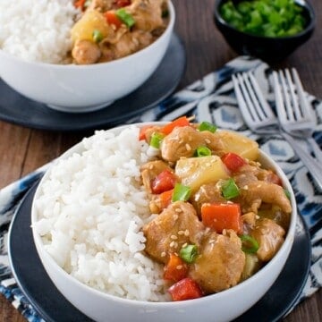 Two white bowls filled with rice and sweet and sour chicken