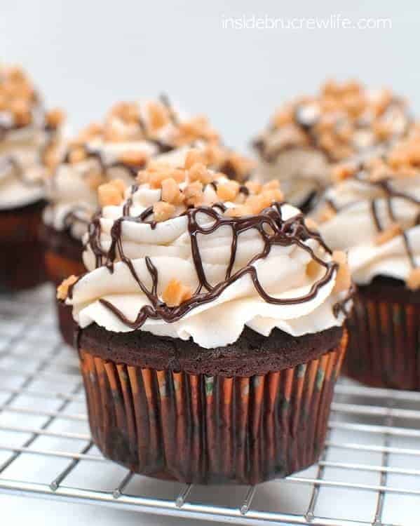 Chocolate drizzles and toffee bits add a fun decoration to the tops of these Toffee Mocha Cupcakes sitting on a wire rack