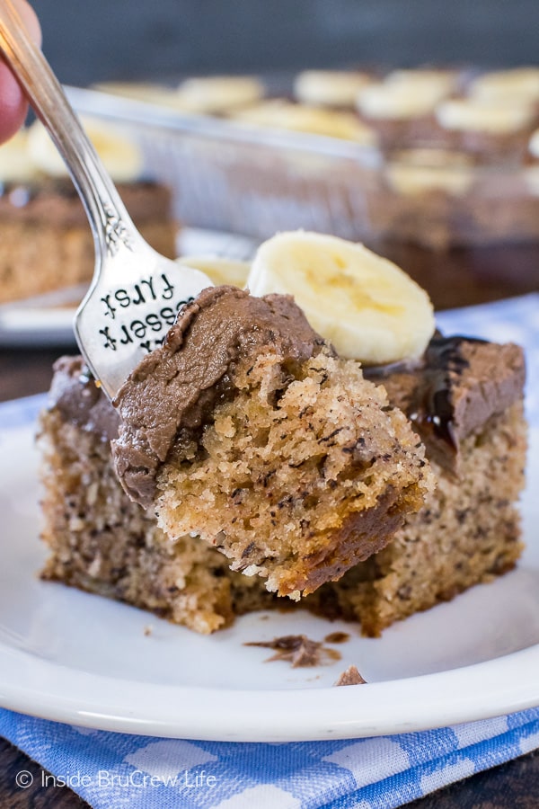 A fork with a bite of best banana cake on it and the rest of the cake behind it