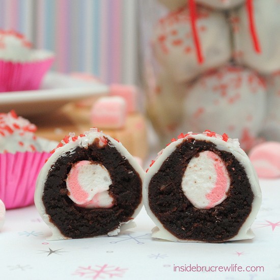 A jar of peppermint marshmallow brownie bites with one brownie bite cut in half in the front