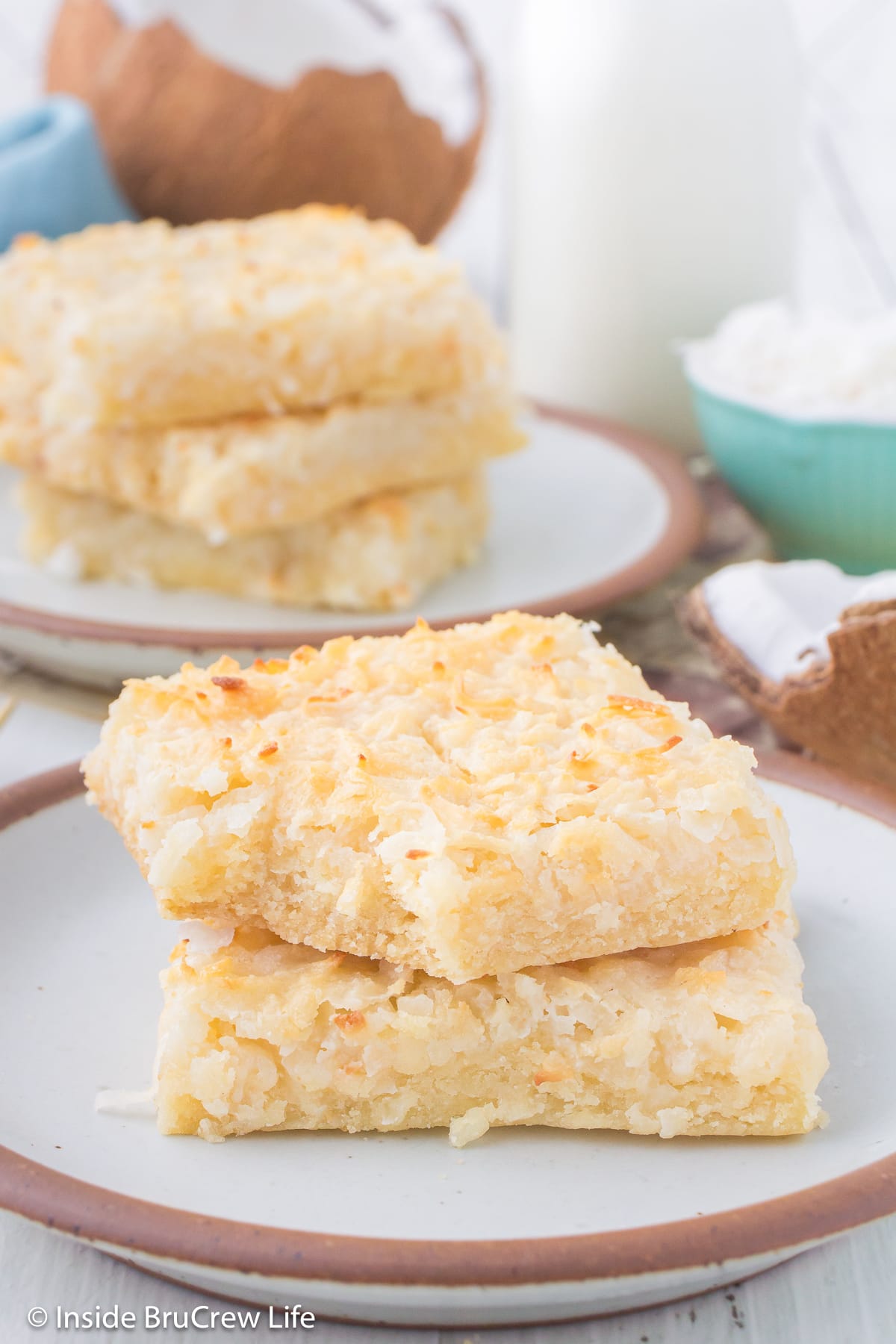 Two butter bars with coconut stacked on a plate.