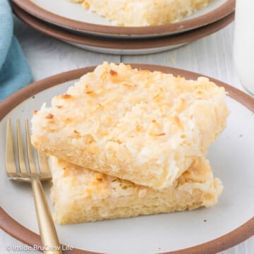 Two coconut cake bars stacked on a plate.