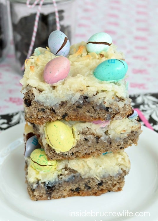 3 cake bars topped with coconut and M&M's that look like Robin Eggs stacked on a white plate.
