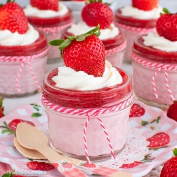 Six clear jars filled with no bake strawberry cheesecake and strawberry chia jam.
