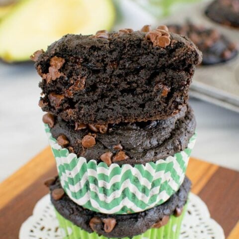 A stack of three chocolate avocado muffins stacked on top of each other.