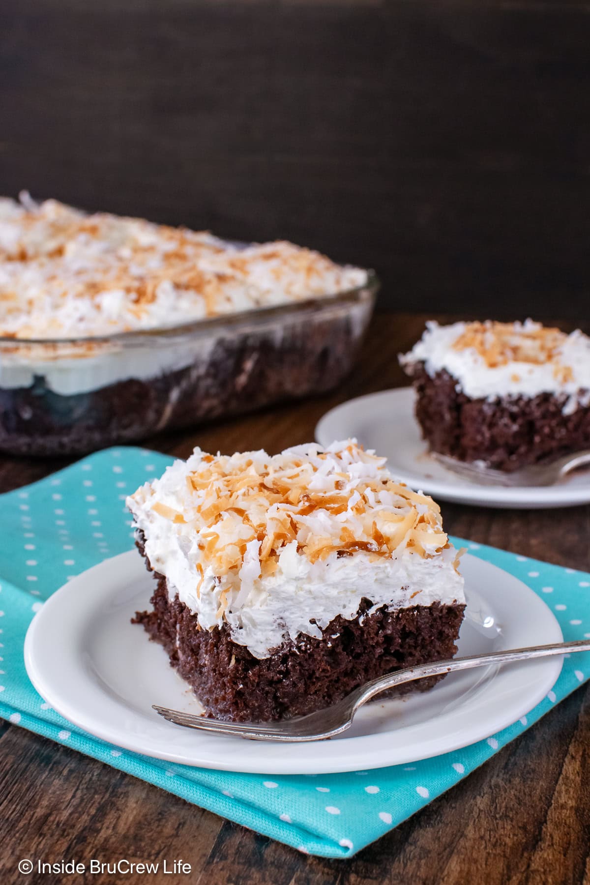 Two squares of chocolate cake topped with whipped cream.