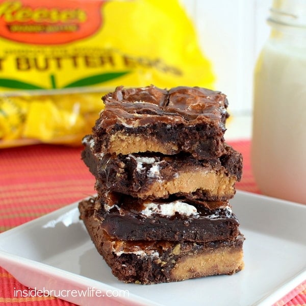 Four Marshmallow Reese's Brownies stacked on top of each other on a white plate.