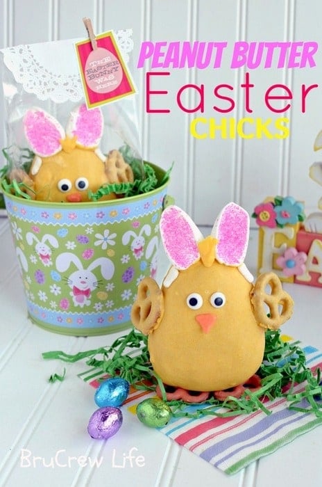 A large Peanut Butter Easter Chick standing on green paper grass surrounded by Easter egg candy.