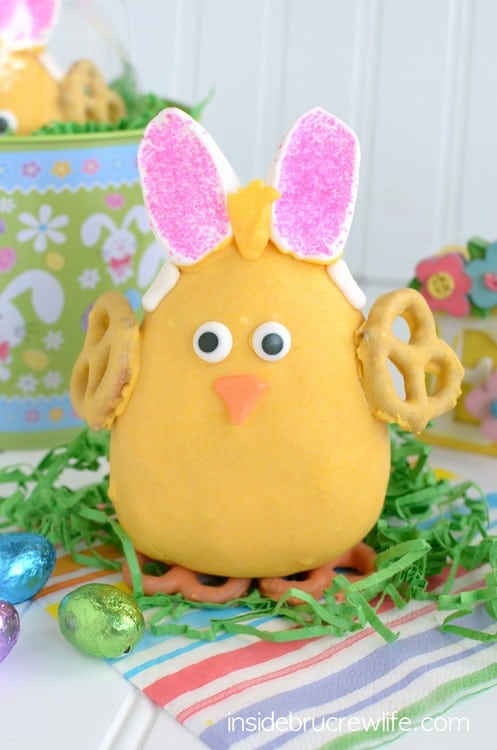 A large Peanut Butter Easter Chick standing on green paper grass surrounded by Easter egg candy.