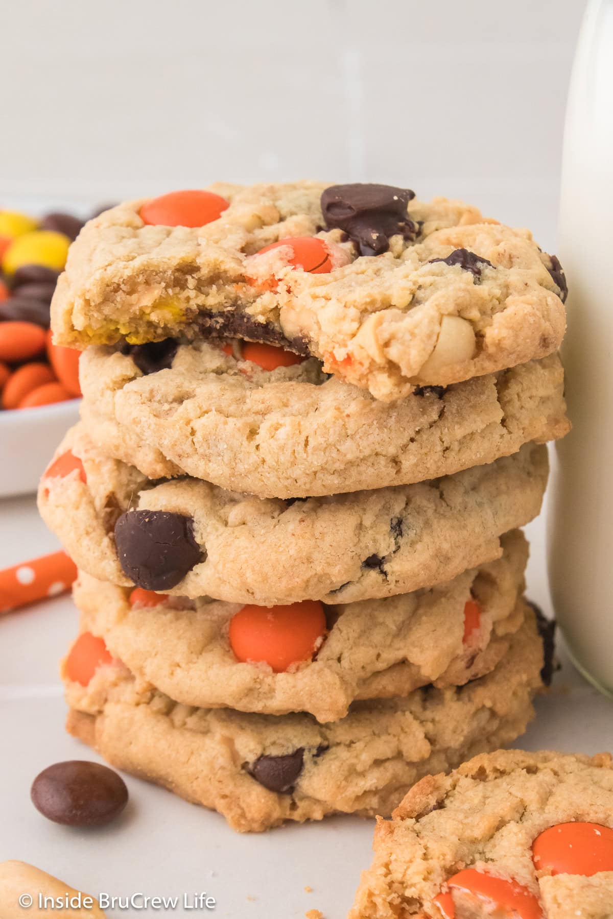 A stack of cookies by a jar of milk.