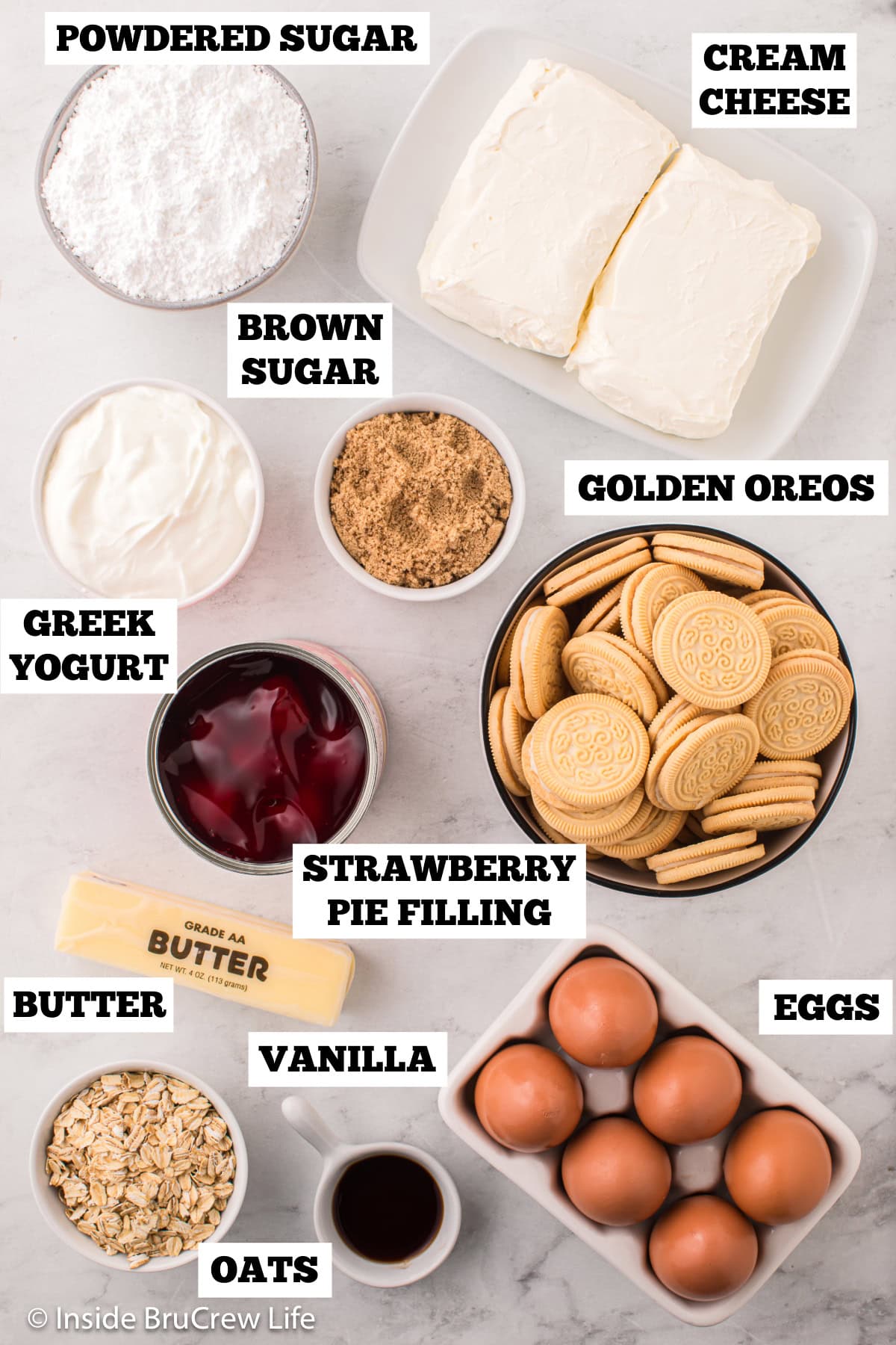 A white board with bowls of ingredients needed to make cheesecake bars with pie filling.