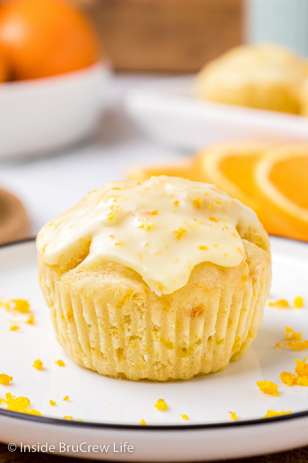 A glazed orange muffin on a white plate.