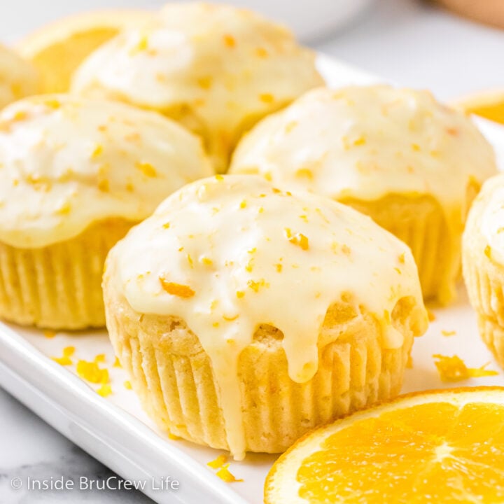 A white tray with glazed orange muffins sitting on it.