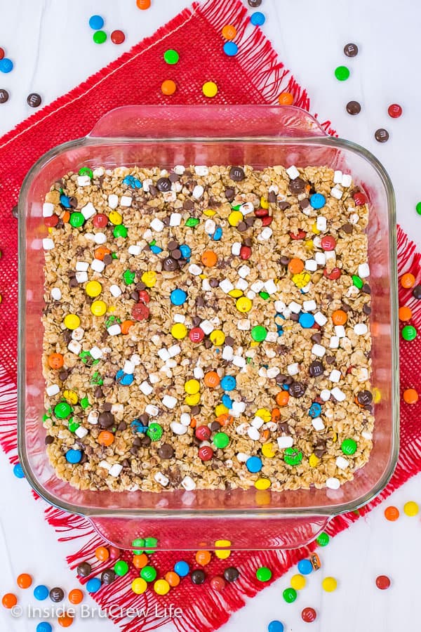 An overhead picture of a pan of M&M granola bars with candies scattered around it.