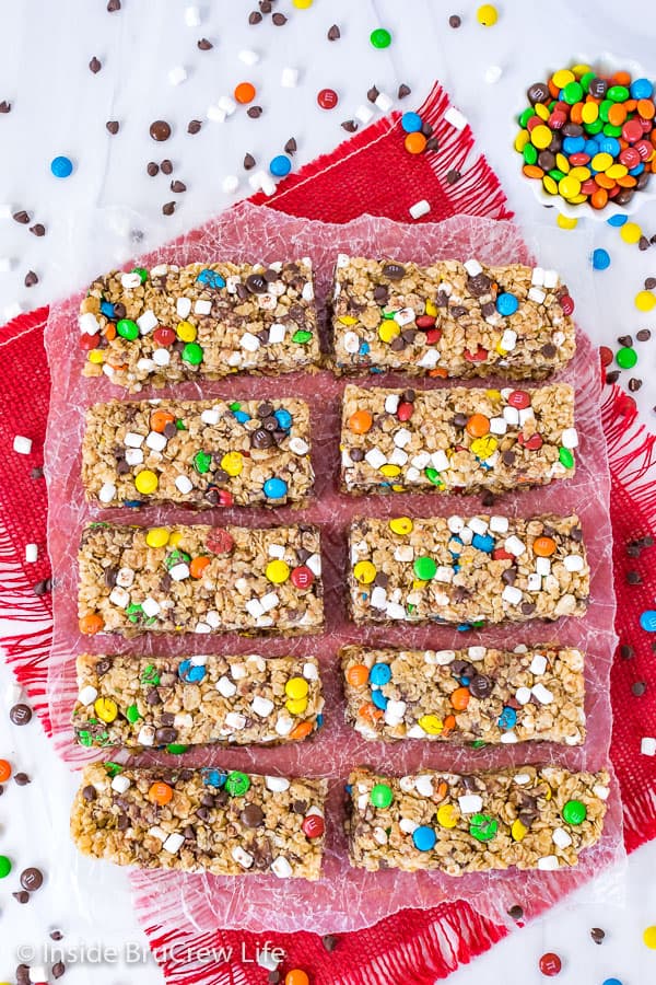 An overhead picture of ten M&M granola bars on wax paper and a red towel.