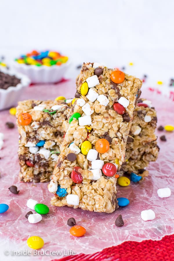 Two M&M granola bars on wax paper with another bar leaning against them.