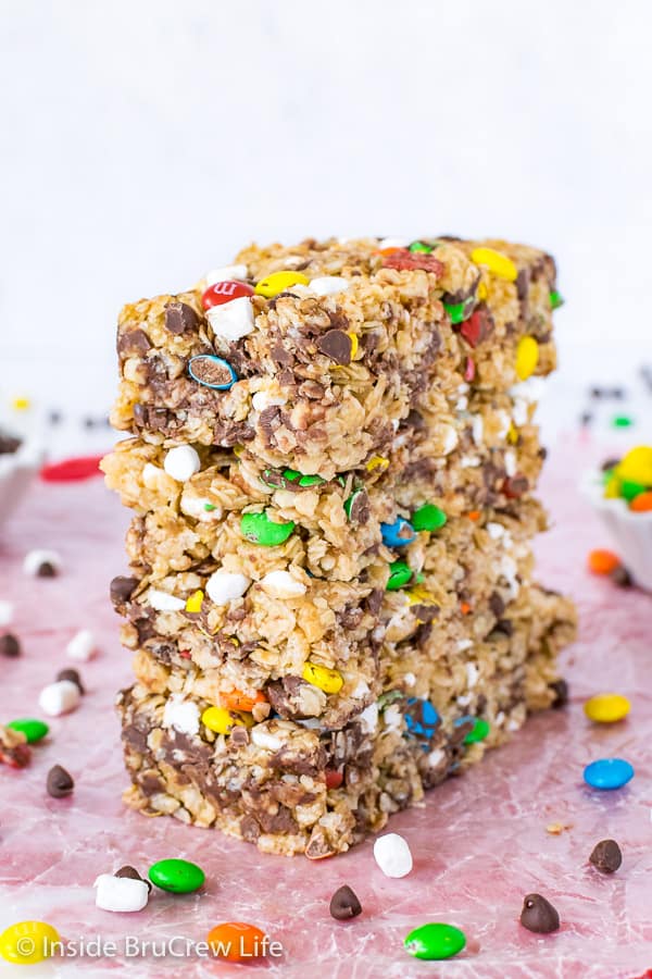 Four M&M granola bars stacked on top of each other with more M&M's scattered around them.