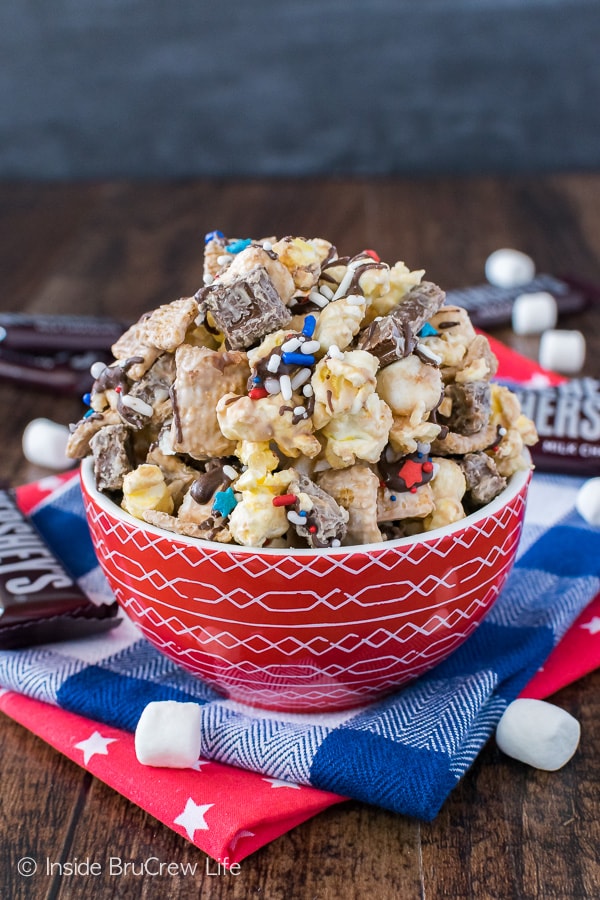 A red bowl on a blue and white checkered towel filled with lots of S'mores Popcorn