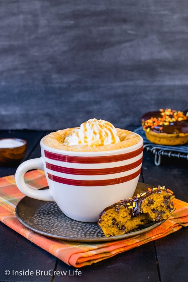 An orange towel with a white mug on it full of salted caramel pumpkin latte and topped with whipped cream and caramel