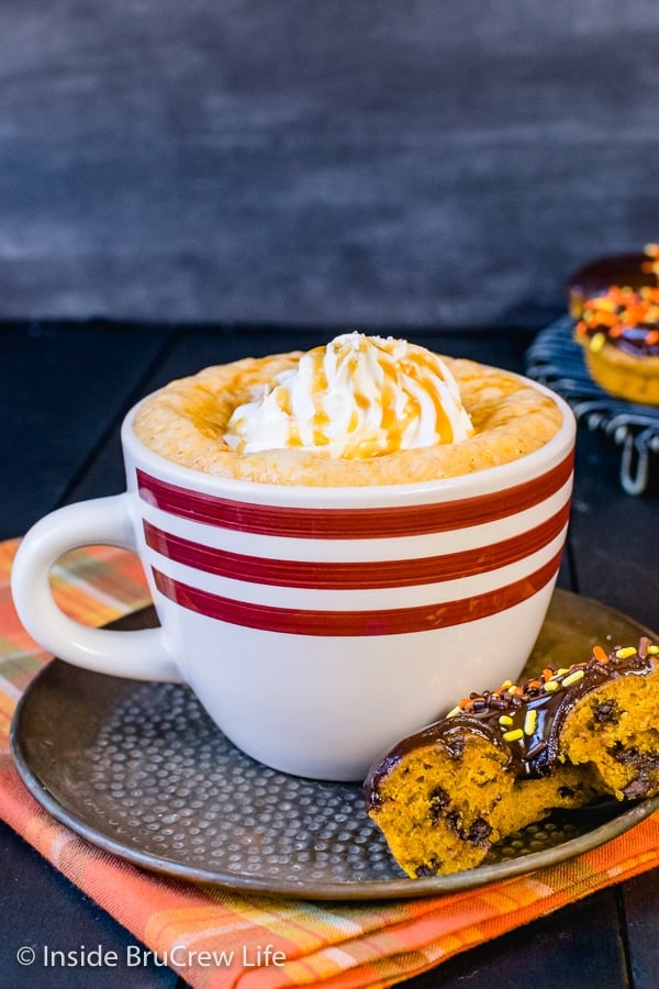 A white mug filled with salted caramel pumpkin latte and topped with whipped cream and caramel drizzles