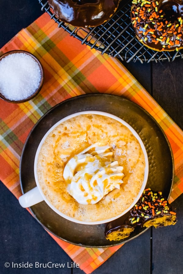 Overhead picture of a mug on an orange towel filled with salted caramel pumpkin latte and topped with whipped cream