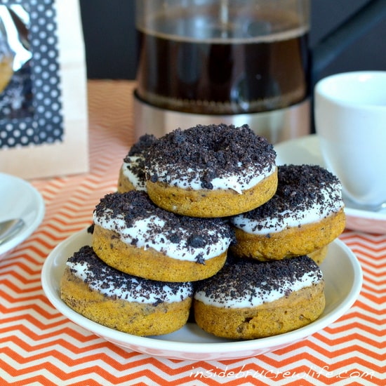 A stack of pumpkin donuts on a white plate.