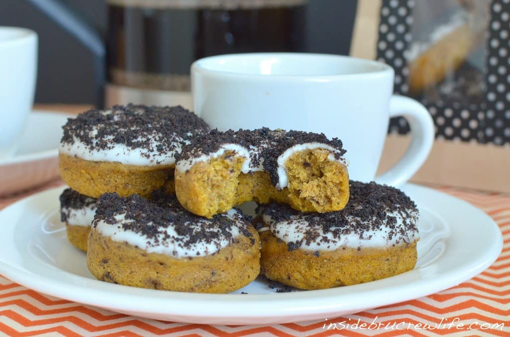 Pumpkin donuts with an Oreo topping on a white plate.