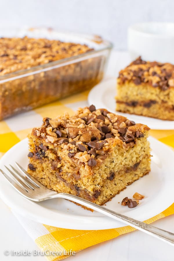 Two slices of banana toffee cake on white plates with a yellow and white towel underneath