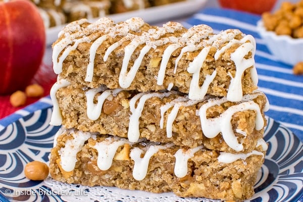 Three granola bars drizzled with white chocolate stacked up on a blue plate.