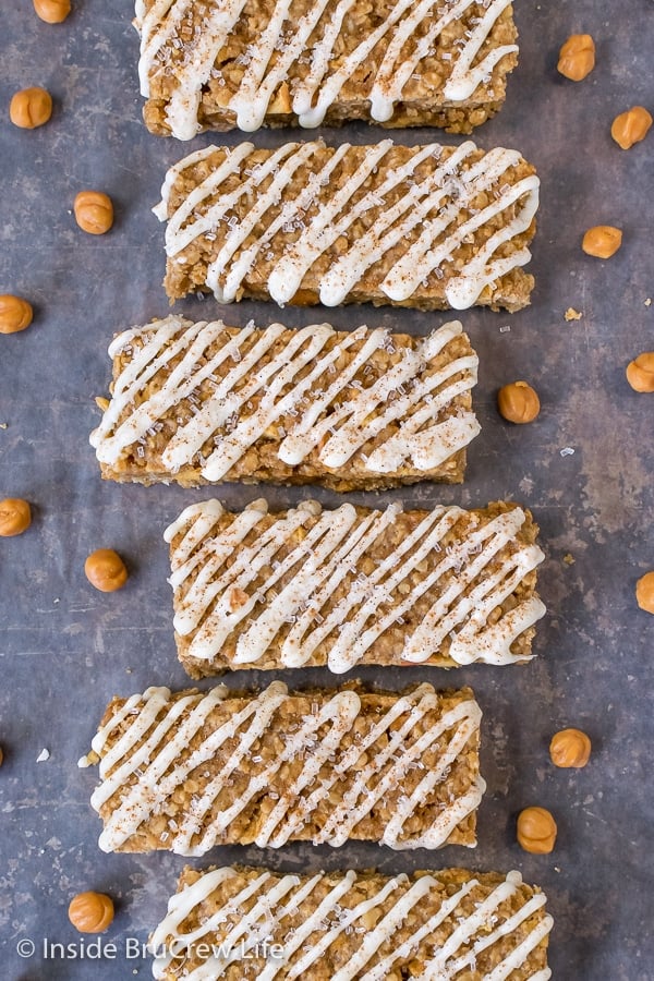 Overhead picture of a line of caramel apple granola bars drizzled with white chocolate .