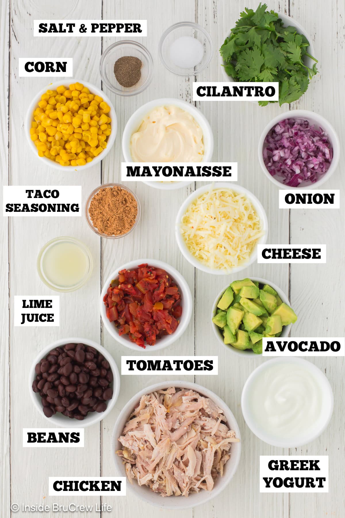 A white board with bowls of ingredients needed to make a chicken salad with a taco dressing.