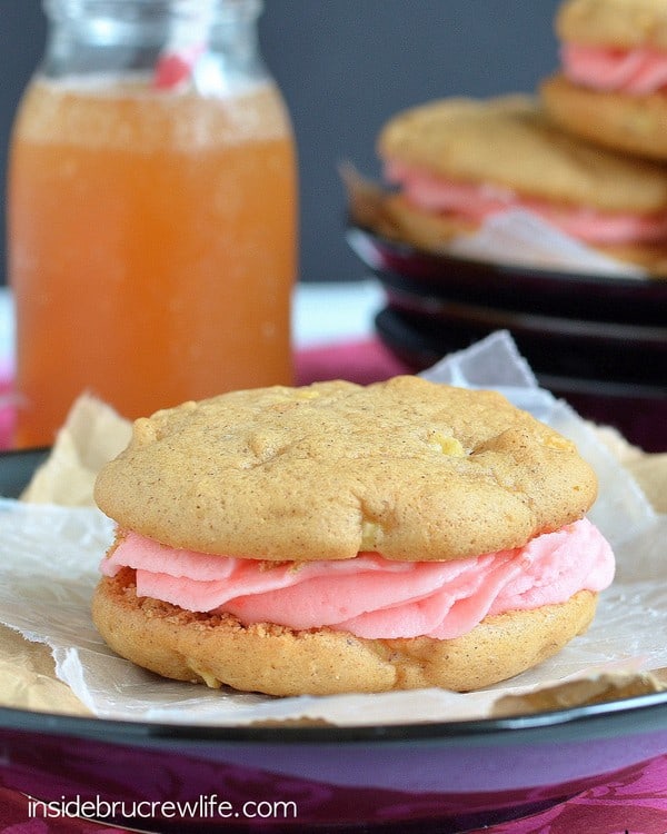 An up close picture of an apple whoopie pie filled with red hot frosting on a black plate