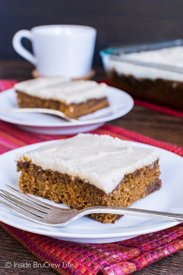 Two squares of apple butter cake with vanilla bean glaze on white plates.